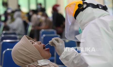 Seorang petugas kesehatan Indonesia berbaju hazmat mengumpulkan sampel spesimen dari calon jemaah haji saat tes swab Covid-19 sebelum jemaah haji Indonesia berangkat ke Mekkah di Puskesmas Tanggerang, Banten, Indonesia, 03 Juni 2022. 