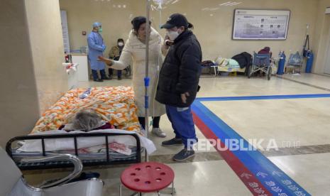  Wanita mengobrol saat pasien lanjut usia di atas tandu menerima perawatan di lorong bangsal darurat di Beijing, Kamis, 19 Januari 2023. 