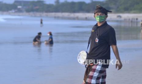 Pecalang atau petugas keamanan adat Bali melakukan pengawasan penerapan protokol kesehatan terhadap pengunjung Pantai Jimbaran di Badung, Bali, Jumat (10/7). Menteri Perencanaan Pembangunan Nasional/Kepala Badan Perencanaan Pembangunan Nasional (PPN/Bappenas) Suharso Monoarfa menyebut Bali aman dikunjungi wisatawan pada masa pandemi. Pasalnya, sistem komunitas adat di daerah itu berpartisipasi mencegah penyebaran Covid-19.