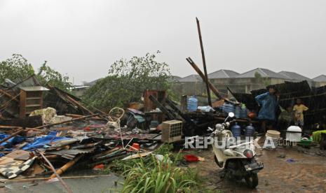 Warga berteduh di balik puing-puing rumah yang roboh akibat angin puting beliung.