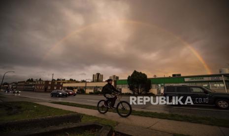  Pelangi melintas di langit di atas pengendara sepeda dan pengendara sepeda motor di Vancouver, British Columbia, Selasa, 24 November 2020. Vancouver bersama komunitas masyarakat adat jajaki peluang jadi tuan rumah Olimpiade.