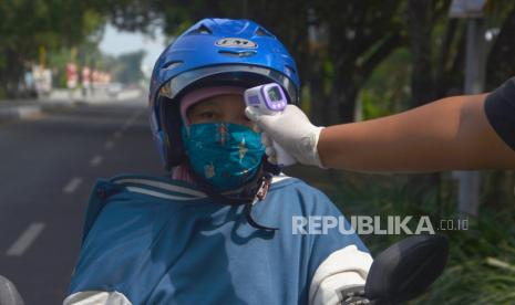 Petugas kesehatan memeriksa suhu tubuh pengendara motor yang melintas di depan pos Keplaksari, Kecamatan Peterongan, Jombang, Jawa Timur, Kamis (28/5/2020). Pemeriksaan tersebut untuk mengantisipasi peningkatan penyebaran virus Corona (COVID-19) di Kabupaten Jombang, karena banyak masyarakat yang sudah mulai kembali beraktivitas di luar rumah