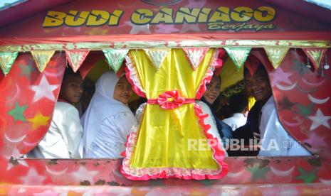 Pasangan pengantin menaiki mobil odong-odong untuk diarak seusai digelarnya nikah massal di Kecamatan Padang Timur, Kota Padang, Sumatera Barat, Selasa (16/5/2023). Sebanyak 18 pasangan mengikuti Isbat terpadu nikah massal yang dicanangkan Pemkot Padang untuk melegalkan status pernikahan mereka secara hukum sekaligus merapikan administrasi kependudukan kota itu.  