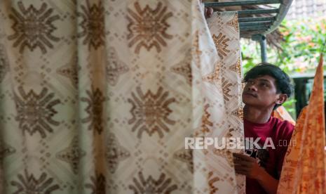 Pekerja menjemur batik khas Lebak motif Gula Sakojor di Imah Batik Sahate, Lebak, Banten, Selasa (29/12/2020). Menteri Koordinator Bidang Perekonomian Airlangga Hartanto mengatakan pangsa Kredit Usaha Rakyat (KUR) untuk sektor produksi pada tahun 2020 mencapai 57,3 persen meningkat dibandingkan tahun 2019 sebesar 52 persen. 