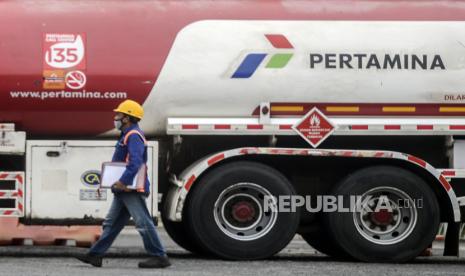 Pekerja melintas di dekat truk tangki Pertamina usai mengisi BBM di TBBM Plumpang, Jakarta, Senin (4/5). Pengamat migas Kurtubi mengingatkan agar harga BBM di dalam negeri tidak ikut naik mengimbangi peningkatan harga minyak dunia yang kembali terjadi.