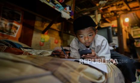 Arga Mahendra siswa MI Ruhul Islam  belajar di rumahnya secara online di kawasan Kampung Penampungan Gasong, Jakarta, Selasa (21/7). Arga belajar menggunakan satu buah handphone yang digunakan secara bergiliran akibat keterbatasan fasilitas smartphone. selain itu warga mengaku mengalami kendala kuota internet akibat keterbatasan pendapatan ekonomi.