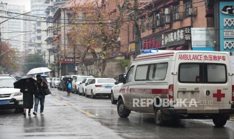 Sebuah ambulans melewati warga yang mengenakan masker untuk membantu melindungi dari COVID-19 di dekat sebuah rumah sakit di Wuhan di Provinsi Hubei, China tengah, Minggu, 23 Januari 2022.