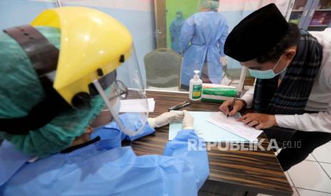 Seorang petugas Indonesia yang mengenakan alat pelindung memeriksa suhu pengunjung saat simulasi imunisasi COVID-19 di Depok, Jawa Barat, Indonesia, 22 Oktober 2020. Setidaknya 2.200 orang relawan di seluruh negeri akan menerima vaksin penyakit COVID-19 di akhir tahun 2020. Pemerintah Indonesia akan memantau kesehatan fisik secara rutin dan jika uji coba terbukti berhasil, pemerintah akan memproduksi 250 juta dosis vaksin pada tahun 2021. EPA-EFE / Bagus Indahono