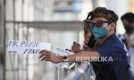  Pekerja hotel menunggu kedatangan tamu di Bandara Internasional Ngurah Rai di Bali, 07 Maret 2022. Pemerintah Indonesia memulai uji coba masuk bebas karantina pada 07 Maret untuk penumpang internasional yang tiba di Bali. Di bawah program uji coba, semua peraturan karantina dimaksudkan untuk dicabut pada April 2022.