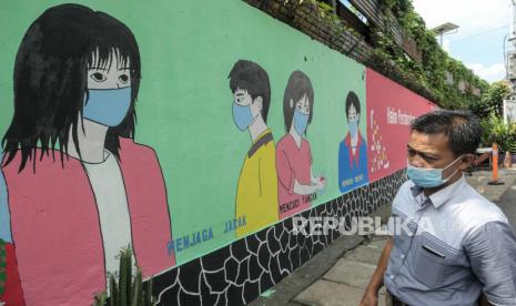 Warga melintasi area mural berisi imbauan penerapan protokol kesehatan di kawasan Halim Perdanakusuma, Jakarta, Rabu (16/6). Mural tersebut menghiasi sepanjang kurang lebih 50 meter dalam rangka menyemarakkan HUT ke-494 Kota Jakarta dengan tema Jakarta Kota Kolaborasi. Selain itu petugas PPSU juga melukis mural berisi pesan imbauan menjaga protokol kesehatan di masa pandemi Covid-19. Republika/Thoudy Badai