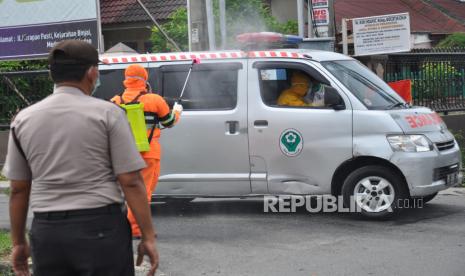 Petugas kepolisian menggunakan alat pelindung diri (APD) menyemprotkan disinfektan di mobil ambulance yang membawa jenazah Pasien Dalam Pengawasan (PDP) untuk dimakamkan di Kota Medan, Sumatera Utara, Senin (30/3/2020). Provinisi Sumut mencatat total kasus terkait COVID-19 yang meninggal di Kota Medan berjumlah 4 orang yakni dua berstatus pasien positif dan dua lainnya berstatus PDP