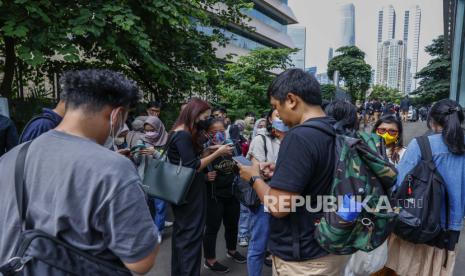 Orang-orang memeriksa ponsel mereka saat berada di luar di tengah kekhawatiran gempa susulan menyusul gempa bumi di kawasan bisnis di Jakarta, Indonesia, 08 Desember 2022. Menurut Badan Meteorologi Indonesia (BMGK), gempa berkekuatan 5,8 melanda tenggara Sukabumi, provinsi Jawa Barat. Gempa dirasakan di gedung-gedung bertingkat di ibu kota dan memaksa para pekerja dievakuasi.