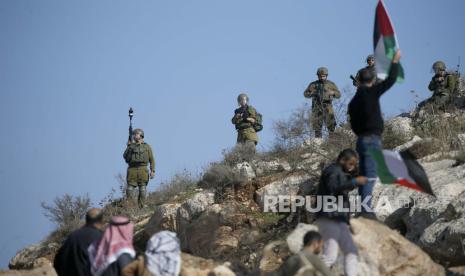 Pengunjuk rasa Palestina menghadapi sekelompok tentara Israel selama bentrokan yang meletus setelah demonstrasi menentang permukiman Israel di tanah Desa Bet Dajan, dekat Kota Nablus di Tepi Barat, 16 Desember 2022. Menurut petugas medis Bulan Sabit Merah Palestina, setidaknya lima warga Palestina terluka dalam bentrokan itu.