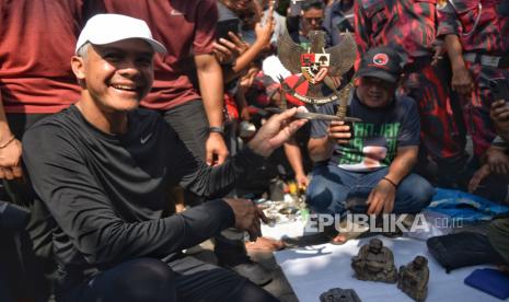 Calon presiden nomor urut 3 Ganjar Pranowo menunjukan barang yang dibelinya saat blusukan di Pasar Klitikan Notoharjo, Surakarta, Ahad (24/12/2023). Dalam kesempatan blusukan di pasar yang dikenal sebagai pasar barang-barang bekas satu-satunya di Solo itu Ganjar Pranowo berbelanja alat pijat serta patung garuda pancasila. Ganjar pun menyempatkan berdialog dengan pedagang dan warga.