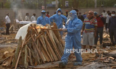 Seorang anggota keluarga, mengenakan Alat Pelindung Diri (APD), melakukan upacara terakhir untuk korban COVID-19 di tempat kremasi di New Delhi, India,  Kamis (29/4). Delhi melaporkan 25.986 kasus baru, 368 kematian dalam 24 jam terakhir dan terus berlanjut. berjuang dengan suplai oksigen.