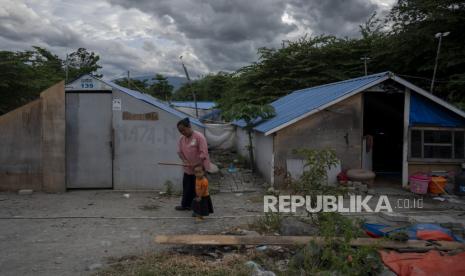 Seorang penyintas bencana tsunami bersama anaknya berjalan di depan hunian sementara (Huntara) yang mereka tempati di shelter Lere di Kelurahan Lere, Kecamatan Palu Barat, Kota Palu, Sulawesi Tengah, Selasa (7/12/2021). Sekitar 100-an kepala keluarga korban bencana tsunami sejak tiga tahun lalu di shelter itu terancam terlantar karena masa pinjam pakai lahan Huntara yang ditempatinya sudah berakhir dan harus dikosongkan dan sementara itu mereka belum mendapatkan hunian tetap (Huntap). 