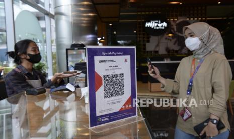 Seorang pelanggan memindai kode batang Quick Response Code Indonesian Standard (QRIS) dengan gawainya saat transaksi melalui aplikasi digital perbankan Bank Muamalat di sebuah kedai kopi di Jakarta, Jumat (28/1/2022). Bank Indonesia memperkirakan transaksi digital banking pada tahun 2022 akan mencapai Rp49.733,8 triliun atau tumbuh 24,83 persen secara tahunan (yoy) bila dibandingkan tahun 2021 yang mencapai Rp39.841,4 triliun. 