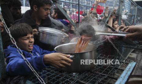 Warga Palestina mengantri untuk menerima makanan gratis di kamp pengungsi Jabaliya di Jalur Gaza pada Senin, (18/3/2024).