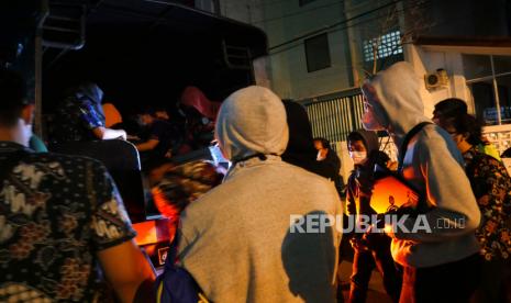 Tersangka menunggu angkutan untuk pemindahan saat penggerebekan kantor pinjaman online ilegal di Samirono, Yogyakarta, Jumat (15/10) dini hari. Tim siber Ditreskrimsus Polda Jabar bersama Polda DIY berhasil menggerebek kantor pinjol ilegal. Sebanyak 86 orang berhasil diamankan, yang selanjutnya dibawa ke Jawa Barat. Selain itu, 105 buah komputer dan 105 telepon genggam juga diamankan dari penggerebekan ini.