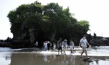 Wisatawan berjalan di tepi pantai saat mengunjungi objek wisata Tanah Lot, Tabanan, Bali, Senin (12/12/2022). Pemerintah Provinsi Bali memastikan tidak ada perubahan kebijakan berkaitan degan berlakunya Undang-Undang KUHP yang baru serta memastikan kenyamanan dan privasi wisatawan melalui penyelenggaraan kepariwisataan Bali yang berkualitas serta bermartabat. 