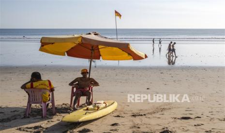 Wisman berjalan-jalan di pantai Kuta, Bali.