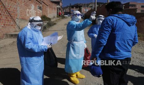 Seorang dokter yang mengenakan alat pelindung penuh mengukur suhu tubuh seorang pria selama uji coba coronavirus dari rumah ke rumah di Villa El Rosal, di pinggiran La Paz, Bolivia, Minggu, 12 Juli 2020. 