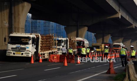 Petugas gabungan mengarahkan kendaraan untuk keluar Tol Cikarang Barat, di ruas Tol Cikampek, Jabar,Ahad (26/042020). Larangan mudik dan sosialisasi aturan Pembatasan Sosial Berskala Besar (PSBB) di ruas tol itu guna mencegah penyebaran COVID-19 dengan membatasi kendaraan pribadi dan angkutan umum yang melintas