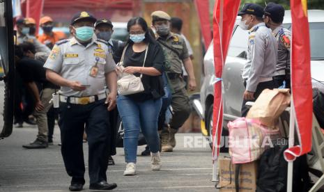 Seorang pemudik yang baru tiba berjalan menuju lokasi tes cepat antigen di Terminal Bus Kalideres, Jakarta, Ahad (23/5). Tes cepat antigen secara random/acak kepada pemudik arus balik tersebut dilakukan untuk mengantisipasi lonjakan kasus positif COVID-19 pasca lebaran.Prayogi/Republika. 