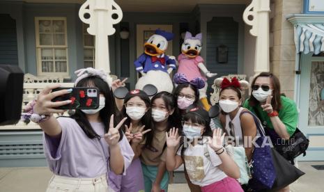 Pengunjung dengan memakai masker berfoto bersama dengan boneka Donald Duck dan Daisy Duck di Hong Kong Disneyland, Jumat (25/9). Hong Kong Disneyland kembali dibuka untuk pengunjung setelah sempat ditutup sementara karena pandemi Covid-19. Foto AP / Kin CheungGaleri Foto