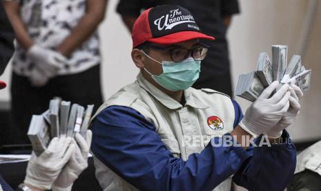 Penyidik KPK menunjukan barang bukti uang tunai saat konferensi pers terkait Operasi Tangkap Tangan (OTT) tindak pidana korupsi pada program bantuan sosial di Kementerian Sosial untuk penanganan COVID-19 di Gedung KPK, Jakarta, Minggu (6/12/2020) dini hari. Dalam operasi tangkap tangan itu KPK menetapkan lima tersangka yakni Menteri Sosial Juliari P Batubara, pejabat pembuat komitmen di Kemensos Matheus Joko Santoso dan Adi Wahyono dan pihak swasta Ardian IM dan Harry Sidabuke  serta mengamankan uang dengan jumlah Rp14,5 miliar. ANTARA FOTO/Hafidz Mubarak A/rwa.