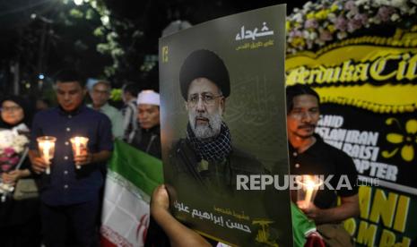 Seorang pria memegang potret Presiden Iran Ebrahim Raisi saat menyalakan lilin di luar Kedutaan Besar Iran di Jakarta, Indonesia, Senin, 20 Mei 2024. 