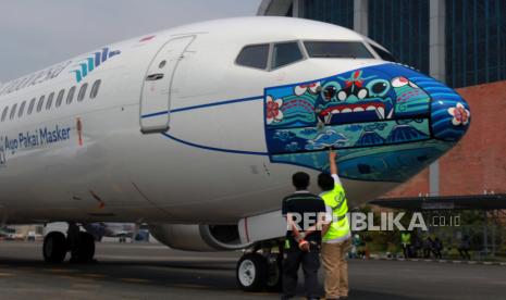 Pekerja melakukan pengecekan akhir livery masker pesawat Garuda Indonesia. Garuda Indonesia pada pekan ini akan membuka tiga rute ke Surabaya-Labuan Bajo (PP), Surabaya-Batam-Medan (PP), dan Solo-Denpasar (PP).