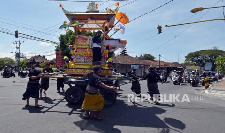 Sejumlah warga mengiringi arak-arakan Wadah atau keranda hias yang berisi jenazah tokoh Puri Kawan Kesiman dalam prosesi upacara Ngaben di Denpasar, Bali. Upacara Ngaben bagi tokoh masyarakat yang biasanya melibatkan ratusan hingga ribuan warga tersebut, saat ini hanya diizinkan diikuti orang dalam jumlah sangat terbatas untuk mengurangi risiko penyebaran wabah Covid-19