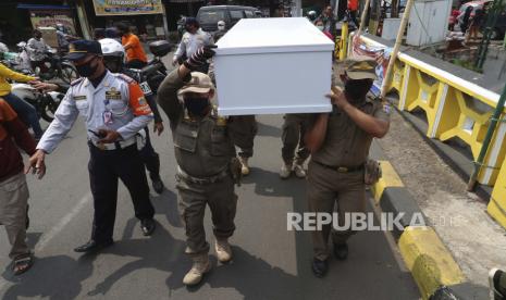 Pejabat pemerintah membawa peti mati tiruan saat mereka berjalan di sekitar persimpangan yang sibuk selama kampanye kesadaran virus corona untuk mengingatkan orang tentang risiko tertular Covid-19 dan untuk selalu mematuhi protokol kesehatan untuk mengekang penyebaran wabah di Jakarta. 