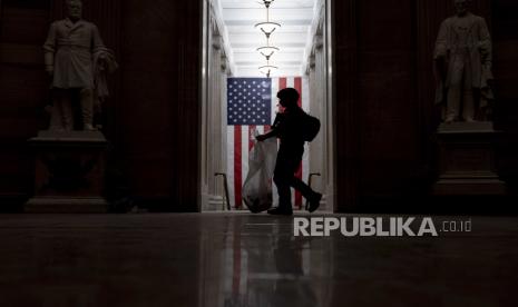  Reaksi Muslim AS Soal Serangan di Capitol. Foto: Seorang petugas polisi ATF membersihkan puing-puing dan barang-barang pribadi yang berserakan di lantai Rotunda pada dini hari Kamis, 7 Januari 2021, setelah pengunjuk rasa menyerbu Capitol di Washington, Rabu.