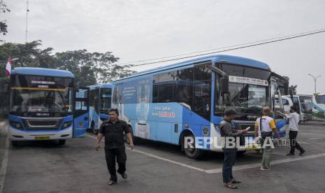 Sejumlah calon penumpang berada di depan bus DAMRI.