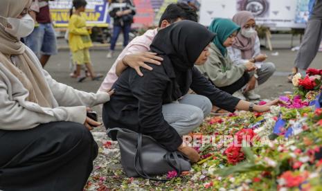 Kerabat berkumpul untuk menyampaikan belasungkawa kepada para korban kerusuhan dan penyerbuan di luar Stadion Kanjuruhan di Malang, Jawa Timur, Indonesia, 06 Oktober 2022. Presiden Indonesia telah memerintahkan penyelidikan dan audit ke semua stadion sepak bola di negara ini, untuk memastikan keamanan untuk para suporter setelah sedikitnya 131 orang tewas dalam kerusuhan dan penyerbuan menyusul pertandingan sepak bola antara Arema FC dan Persebaya Surabaya di Jawa Timur pada 01 Oktober 2022.