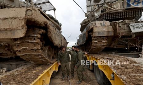 Israeli soldiers stand next to Merkava tanks from the Reserve Brigade 4 loaded on trucks after they pulled out from southern Gaza Strip, at an undisclosed location in Israel, 28 January 2024. More than 26,200 Palestinians and at least 1,330 Israelis have been killed, according to the Palestinian Health Ministry and the Israel Defense Forces (IDF), since Hamas militants launched an attack against Israel from the Gaza Strip on 07 October 2023, and the Israeli operations in Gaza and the West Bank which followed it.  