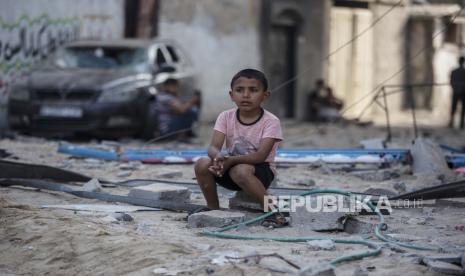 Seorang anak laki-laki Palestina duduk melihat orang lain memeriksa kerusakan toko mereka setelah serangan udara Israel di kamp pengungsi Jabalia, Jalur Gaza utara. Empat anak meninggal dalam serangan di kamp pengungsi Jabalia di utara Jalur Gaza. Ilustrasi.