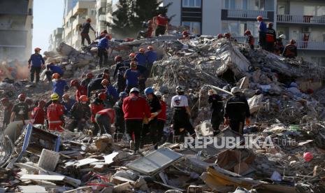 Anggota layanan penyelamatan mencari di puing-puing bangunan yang runtuh untuk orang-orang yang selamat di Izmir, Turki, Minggu, 1 November 2020.Tim penyelamat terus membajak melalui blok beton dan puing-puing bangunan yang runtuh di kota terbesar ketiga Turki untuk mencari korban selamat dari sebuah gempa kuat yang melanda pantai Aegean Turki dan utara pulau Samos Yunani, Jumat 30 Oktober, menewaskan puluhan dan ratusan lainnya terluka. 