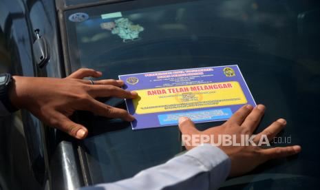 Petugas menempelkan stiker pelanggaran parkir pada kaca mobil yang parkir sembarangan di marka biku-biku Jalan Pasar Kembang, Yogyakarta, Selasa (30/5/2023). Penertiban parkir liar di Jalan Pasar Kembang dilakukan petugas gabungan Satlantas Polresta Yogyakarta, Dishub Kota Yogyakarta, dan Satpol PP Kota Yogyakarta. Hal ini dilakukan untuk keselamatan dan kenyamanan berlalu-lintas di area wisata. Selain itu, juga banyaknya kendaraan yang berhenti serta parkir liar saat sore dan malam. Untuk mengantisipasi petugas memasang water barrier dan pita larangan melintas sepanjang 400 meter di Jalan Pasar Kembang.