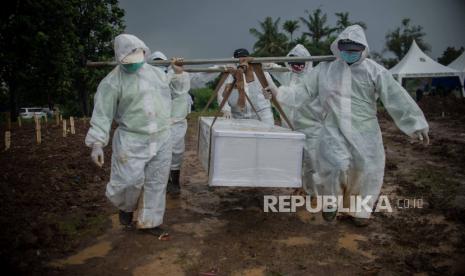 Petugas menggunakan pakaian alat pelindung diri (APD) saat memakamkan jenazah pasien Covid-19.