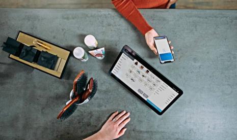 Person holding smartphone beside tablet computer. (Unsplash/Blake Wisz)