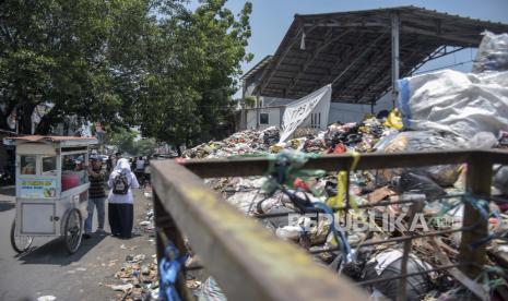 Warga melintas di samping tumpukan sampah di TPS Pagarsih 