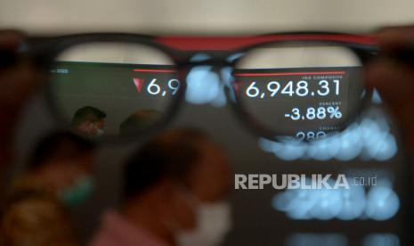 Karyawan melintas di depan layar pergerakan Indeks Harga Saham Gabungan (IHSG), Bursa Efek Indonesia, Jakarta, Senin (9/5/2022). 