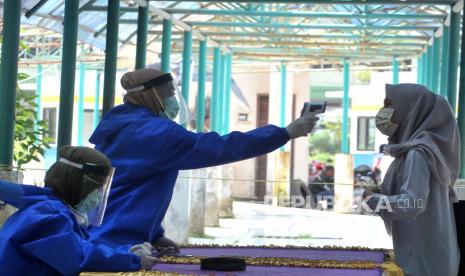 Petugas kesehatan yang dilengkapi dengan Alat Pelindung Diri (APD) memeriksa suhu salah satu penumpang yang turun di terminal Alang Alang Lebar  Palembang,Sumsel.  Jajaran Kepolisian Daerah Sumatera Selatan yang tersebar di 17 kabupaten/kota bersama instansi terkait dan TNI berupaya maksimal mengawal penerapan larangan mudik bagi masyarakat memasuki bulan suci Ramadhan dan menjelang Hari Raya Idul Fitri 1441 Hijriyah.