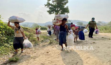 Foto selebaran menunjukkan para pengungsi dari Myanmar membawa barang-barang mereka untuk menyeberangi sungai untuk kembali ke rumah mereka, di kota perbatasan Mae Sot, Thailand .