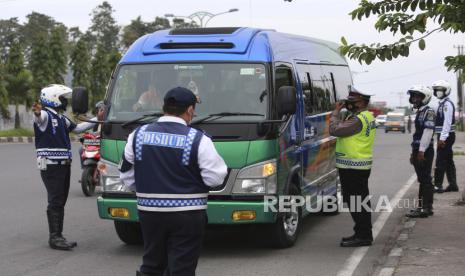 Petugas gabungan menghentikan kendaraan menjelang libur Idul Fitri untuk menekan penyebaran Covid-19 di pos pemeriksaan di pinggiran Kota Medan, Provinsi Sumatra Utara, Indonesia, 7 Mei 2021.