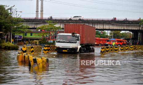 Truk kontainer menerobos banjir rob di Pelabuhan Tanjung Emas, Semarang, Jawa Tengah, Kamis (26/5/2022). Aktivitas Pelabuhan Tanjung Emas masih lumpuh imbas banjir rob. Namun, angkutan peti kemas mulai masuk ke pelabuhan meski masih sedikit. Sementara itu, air rob mulai surut pascaperbaikan tanggul yang jebol.