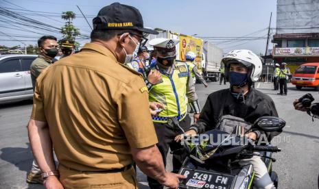 Gubernur Jawa Barat Ridwan Kamil berbincang dengan pengendara kendaraan dengan plat nomor luar Bandung saat melakukan pemantauan posko penyekatan larangan mudik di gerbang Tol Padalarang, Kabupaten Bandung Barat, Senin (10/5). Pada hari kelima penerapan larangan mudik Lebaran 2021, petugas gabungan di posko penyekatan larangan mudik Padalarang telah memutarbalikan sedikitnya 30 kendaraan berplat luar kota karena tidak memiliki surat kesehatan serta ijin perjalanan. Foto: Republika/Abdan Syakura